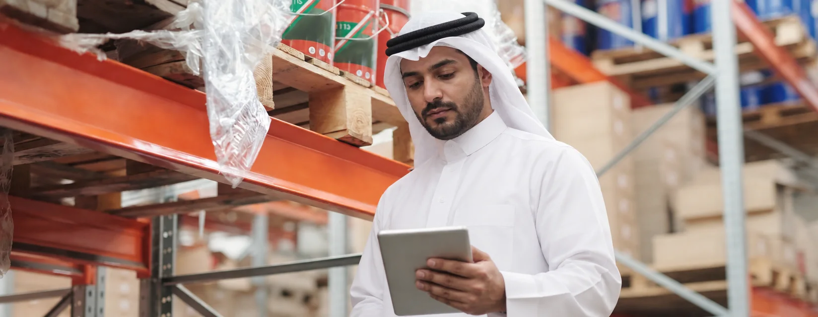 موظف سعودي يحمل جهازاً لوحياً في مستودع